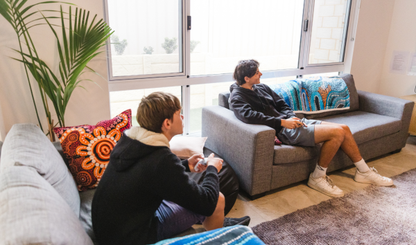 two teenage boys sitting on couches in a living room in Djinda